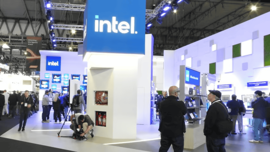 Visitors engage at the Intel booth during a global tech exhibition, showcasing advanced chip innovations and digital displays under bright lighting.