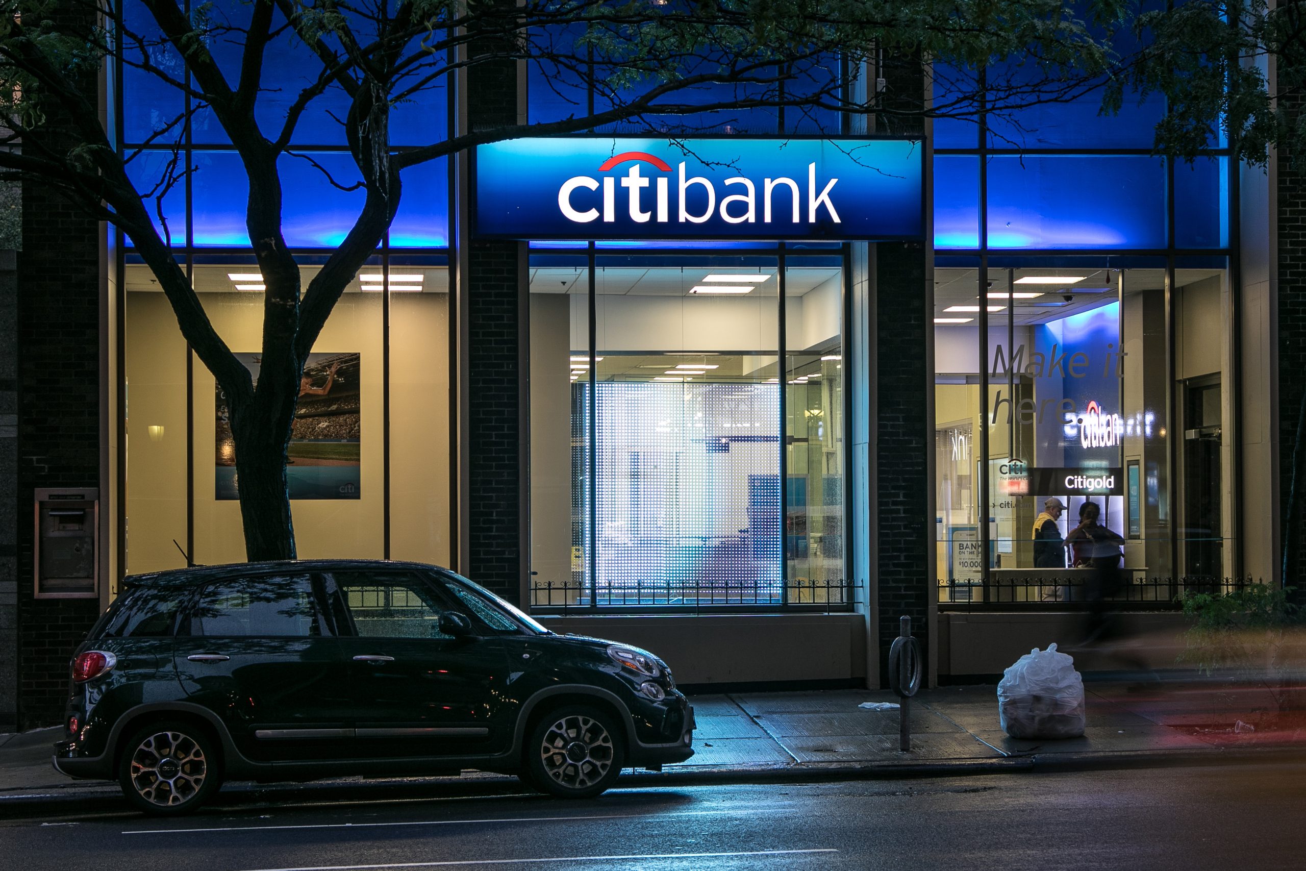Exterior of a Citibank branch at night with illuminated signage and visible interior activity, symbolizing global banking accessibility and Citigroup’s financial services presence in urban centers.