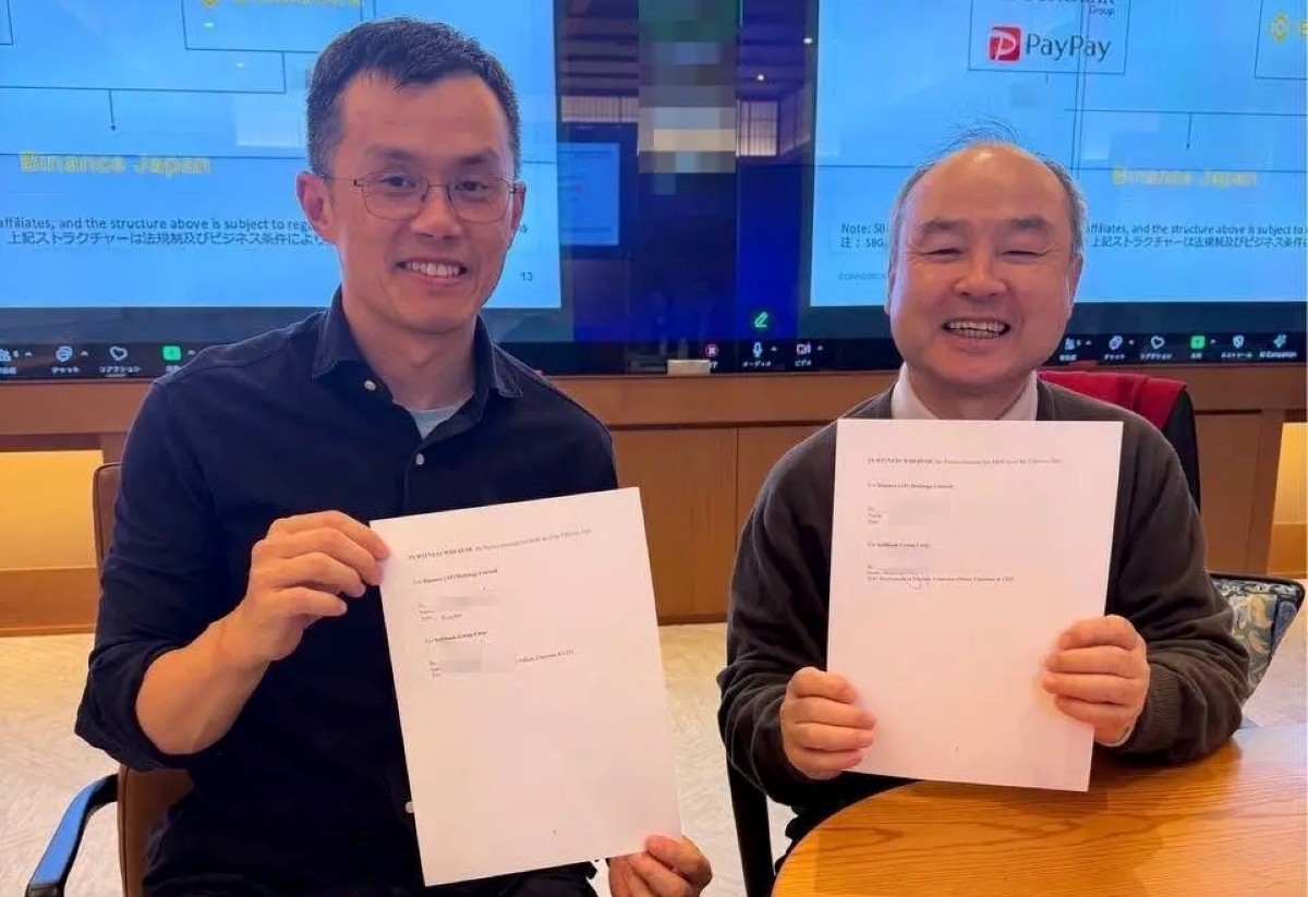 Executives from Binance and SoftBank holding partnership documents during collaboration meeting in Tokyo.