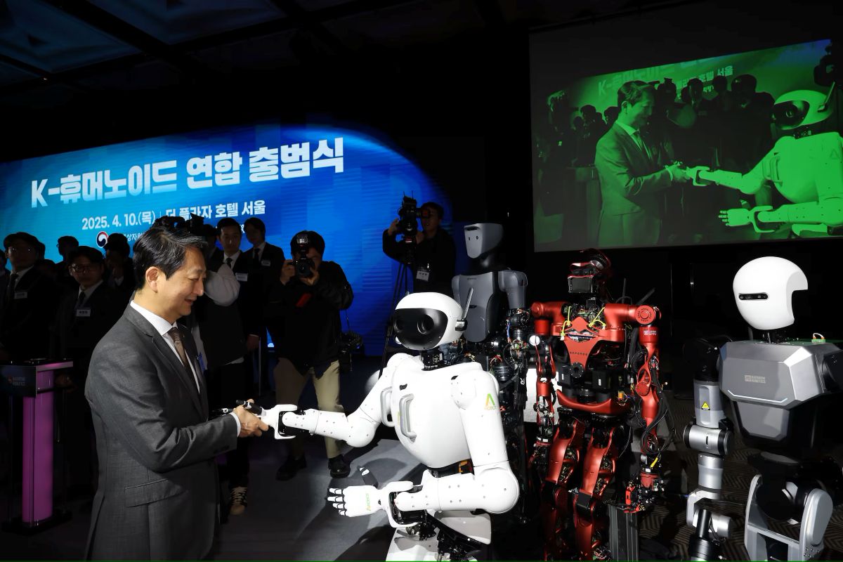 South Korean minister shakes hands with humanoid robot at 2025 K-Humanoid launch event in Seoul, surrounded by photographers and robots on display