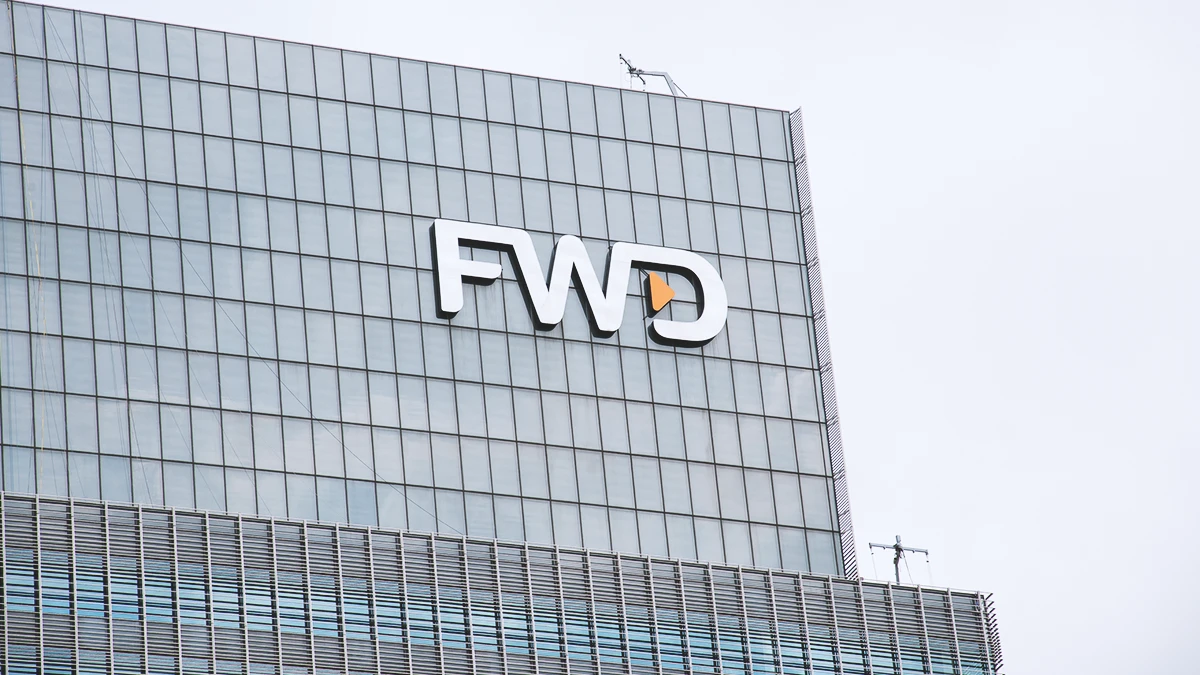 FWD Insurance logo displayed on the glass facade of a high-rise office building under a cloudy sky.