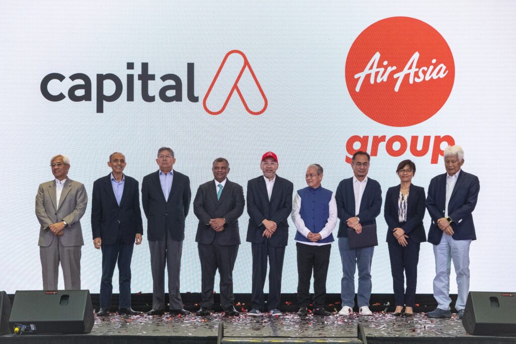 AirAsia Group and Capital A executives pose on stage during a corporate event, standing in front of branded logos to mark a strategic announcement