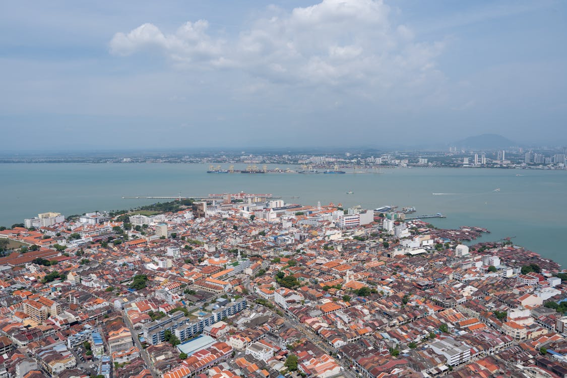 Aerial view of George Town, Penang, Malaysia with coastal skyline and historic rooftops.