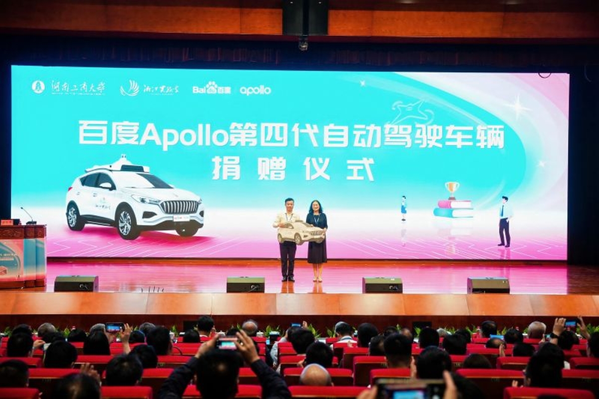 Baidu Apollo donates its fourth-generation autonomous vehicle during a formal ceremony at a university auditorium in China, highlighting AI-driven mobility advancements.