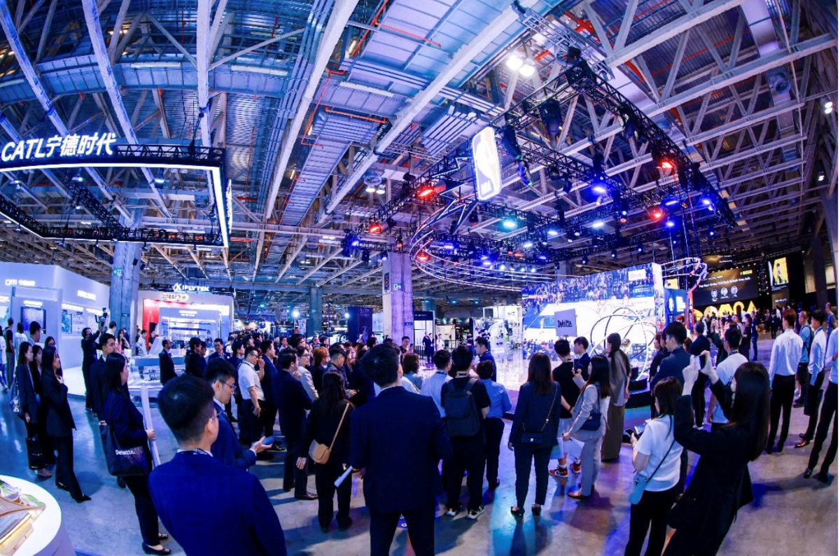 Crowd attending a high-tech trade show in Asia featuring exhibits from CATL, Deloitte, and NBA China, showcasing innovations in technology, energy, and sports under a dynamic, futuristic lighting setup.