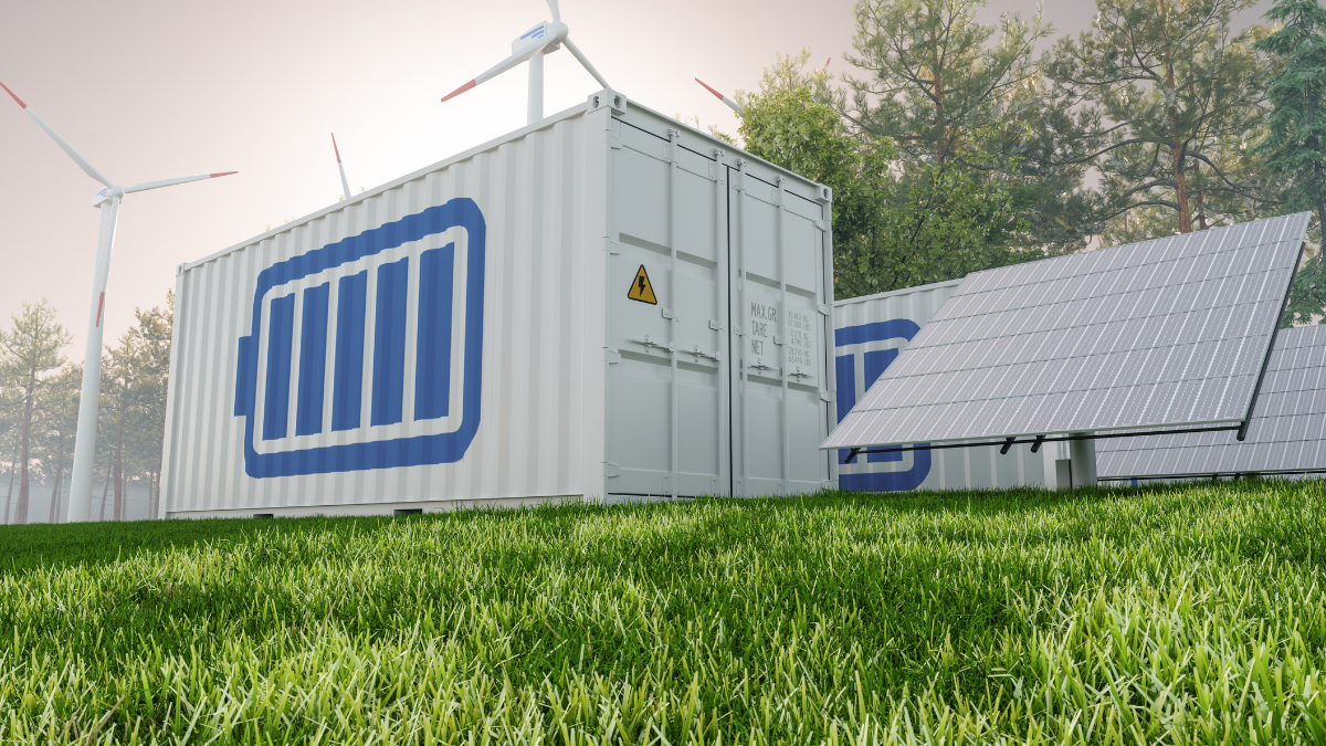 A clean energy facility featuring large battery storage containers with a power icon printed on them. The containers are surrounded by wind turbines and solar panels, symbolizing renewable energy integration. The foreground shows vibrant green grass, while the background is filled with tall trees under a hazy sky, emphasizing the harmony between technology and nature.