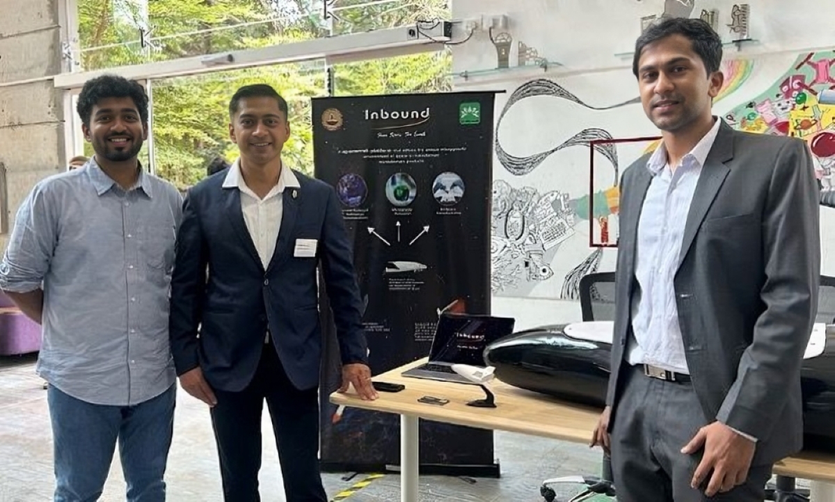 Three men presenting a futuristic underwater drone prototype at a tech showcase event, featuring branding for Inbound and marine innovation visuals in a modern co-working space.