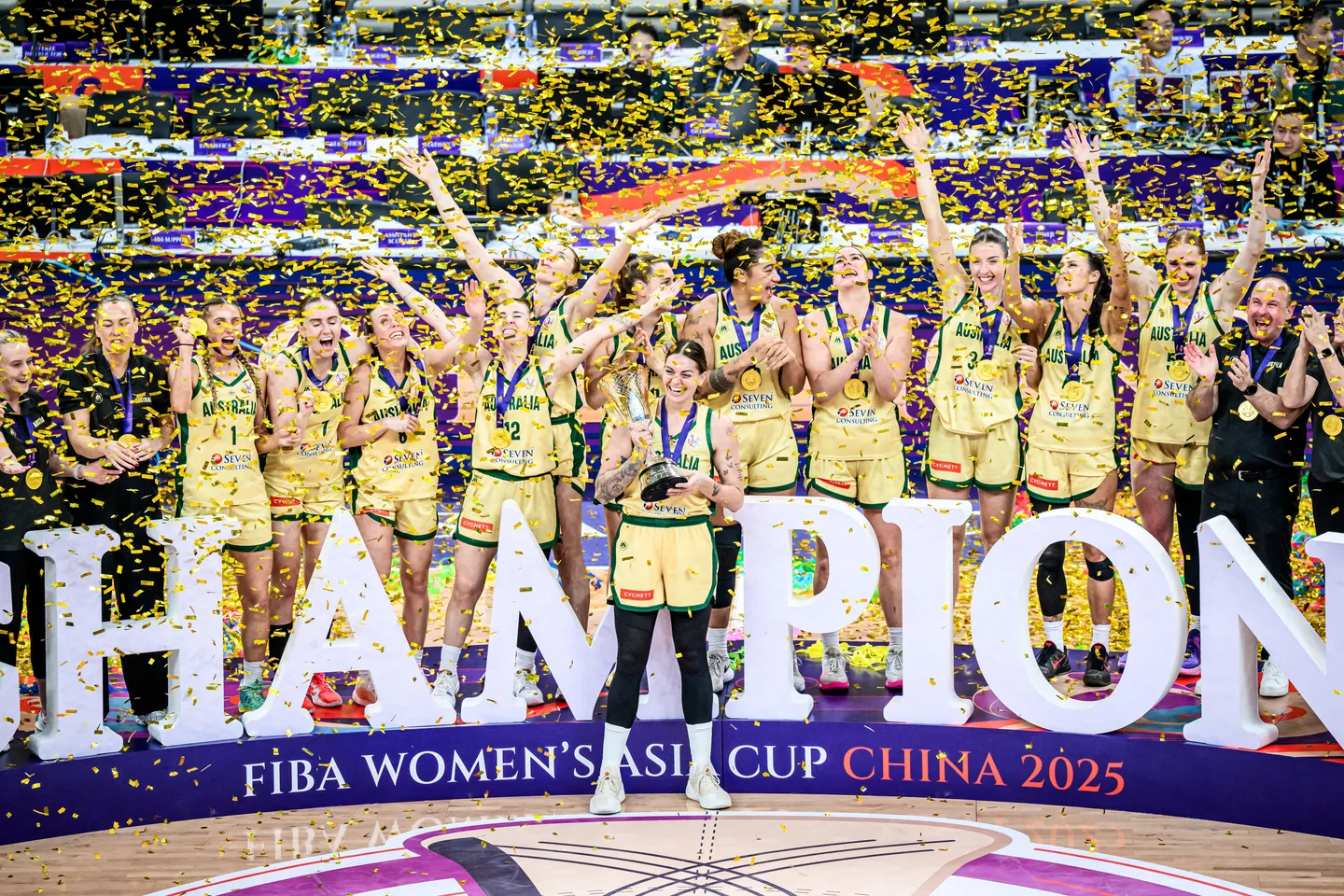 Australia’s women’s basketball team celebrates winning the FIBA Women’s Asia Cup China 2025, holding the championship trophy amid gold confetti, symbolizing excellence in Asia-Pacific sports.