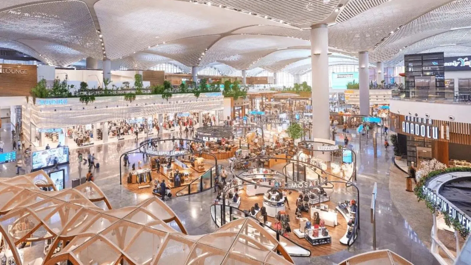 Interior view of a modern international airport terminal featuring expansive retail zones, branded duty-free shops, and a high-tech architectural ceiling, showcasing global travel luxury and commercial design.