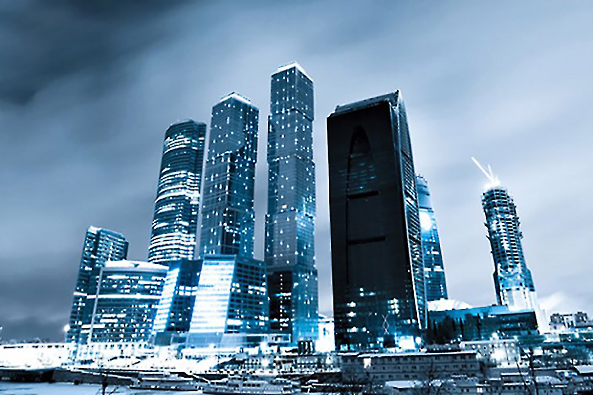Futuristic skyline of India International Business Center at night, featuring illuminated skyscrapers with reflective glass facades under a cloudy sky.