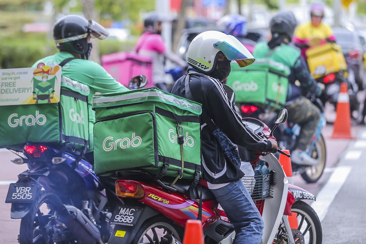 GrabFood delivery riders on motorcycles waiting with green Grab boxes, representing food delivery services in Southeast Asia.
