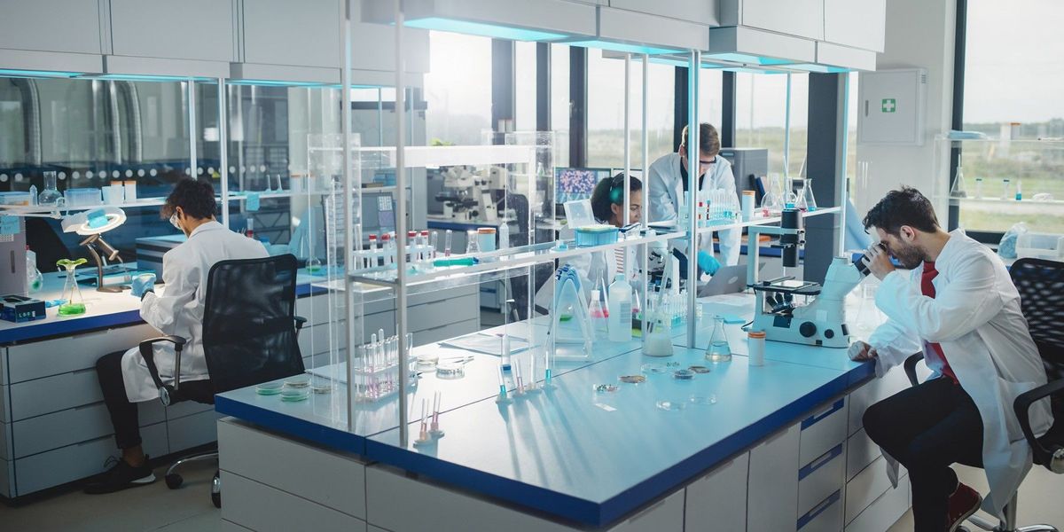 Scientists in a modern laboratory working with microscopes, test tubes, and lab equipment for medical and biotechnology research.