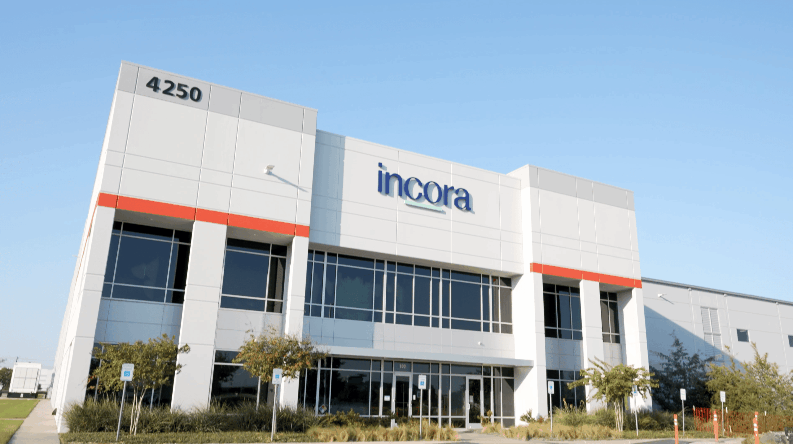 Exterior view of Incora corporate headquarters building with modern architecture, glass windows, and company logo under a clear blue sky.