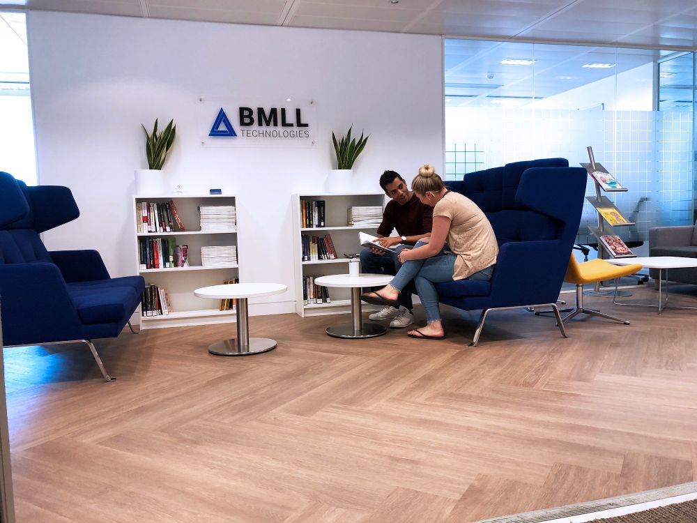 Employees meeting in the BMLL Technologies office lounge with branded signage and modern seating.